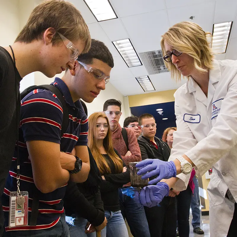 Students looking at science object help by scientist