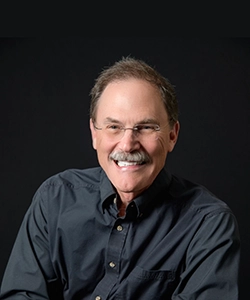 Professional gentleman with a thick mustache, wearing glasses and a black button up shirt.