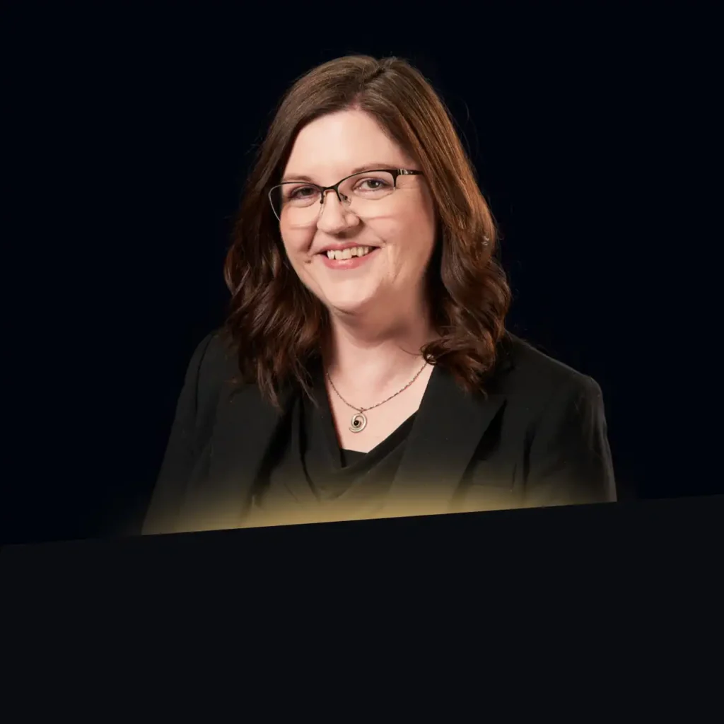 Anita Bell headshot wearing black blazer with gold glow at the bottom of photo