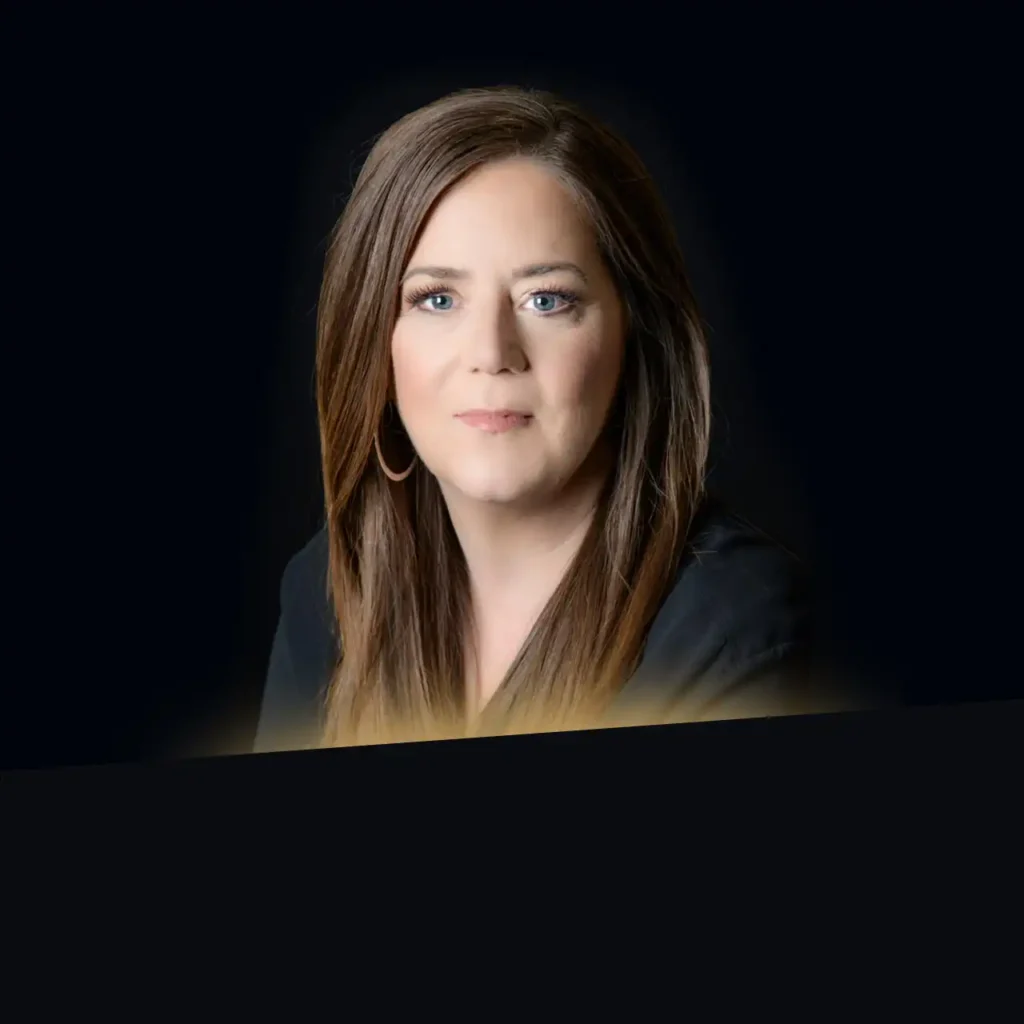 Headshot of Carol Stewart wearing a black blazer with gold glow at the bottom