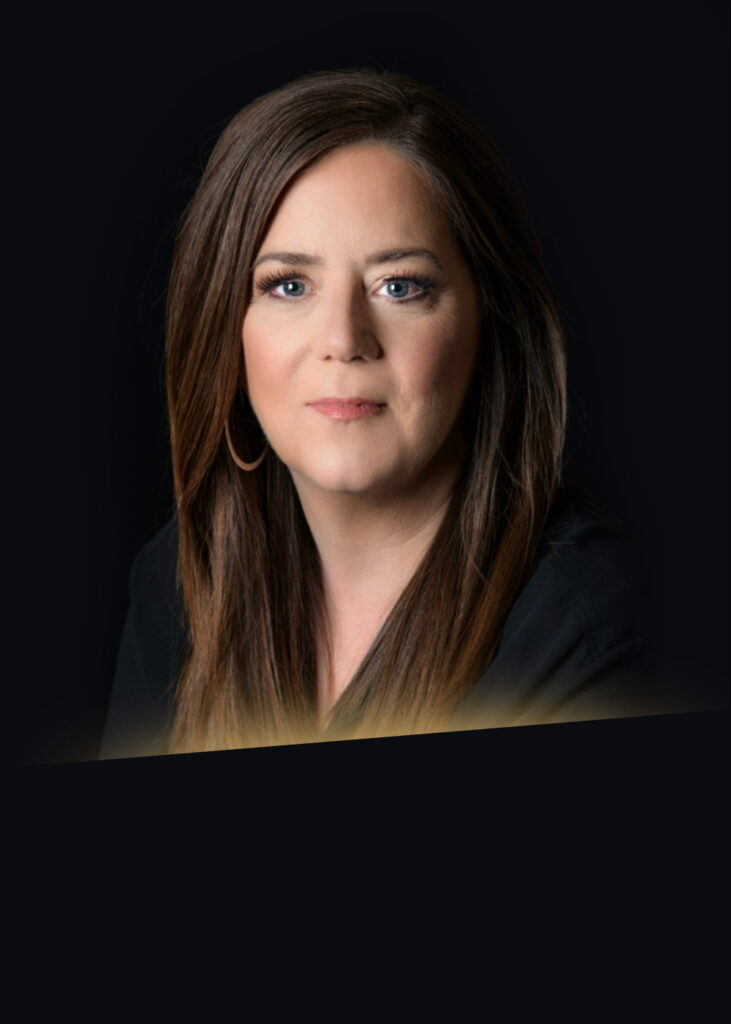 Headshot of Carol Stewart in black blazer with gold glow at bottom