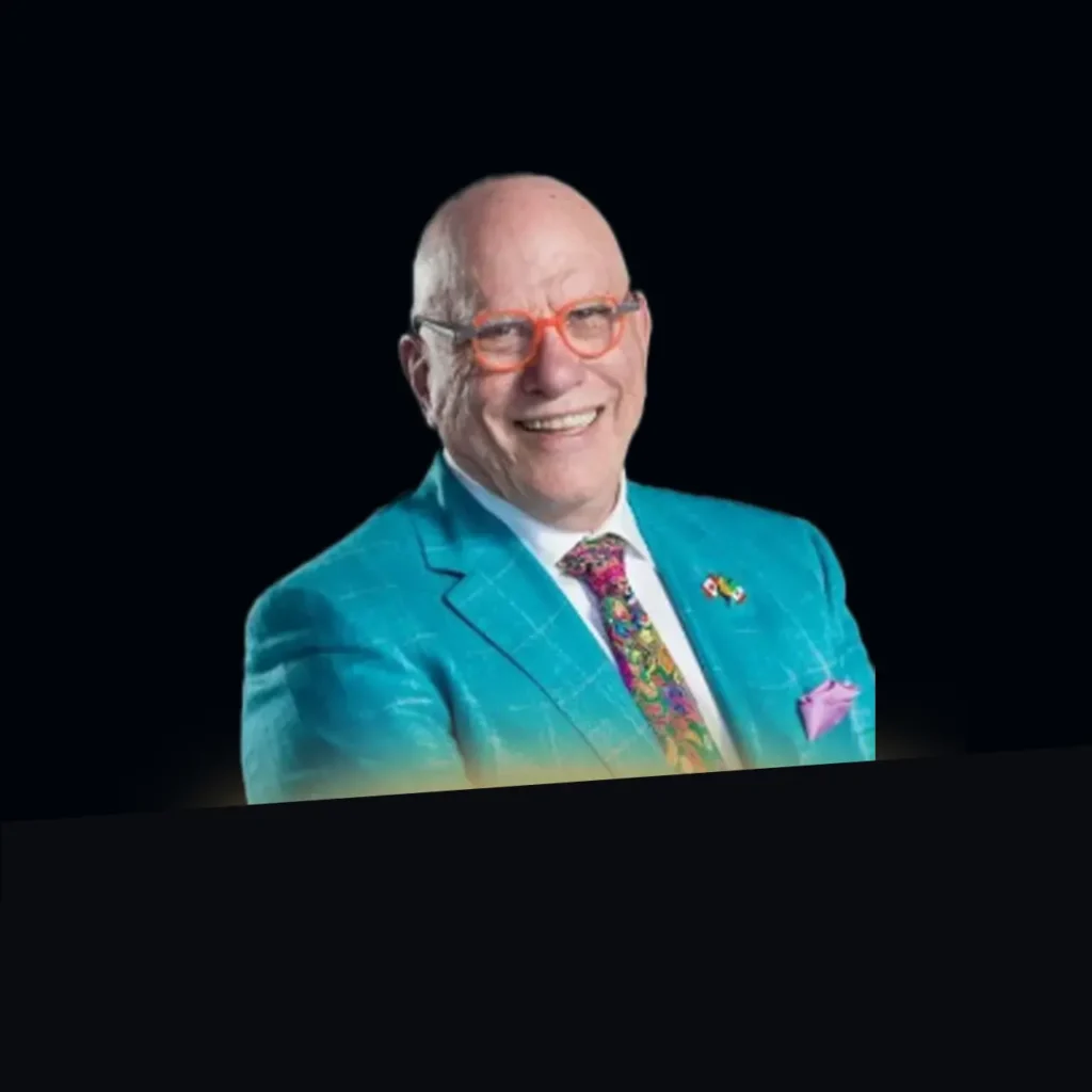 Glen Williamson headshot wearing a turquoise blazer and multi-colored tie with gold glow