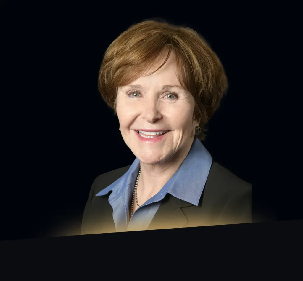 Jan Lesher headshot wearing black blazer and blue button down with gold glow at the bottom at the photo