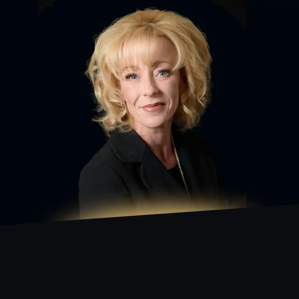 Headshot of Tracy Bibeau wearing a black blazer with gold glow at the bottom
