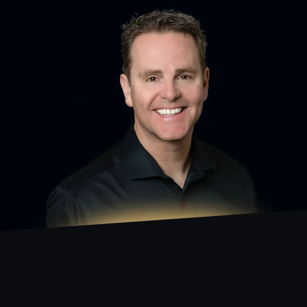 Headshot of Patrick Murphy wearing a black blazer with gold glow at the bottom