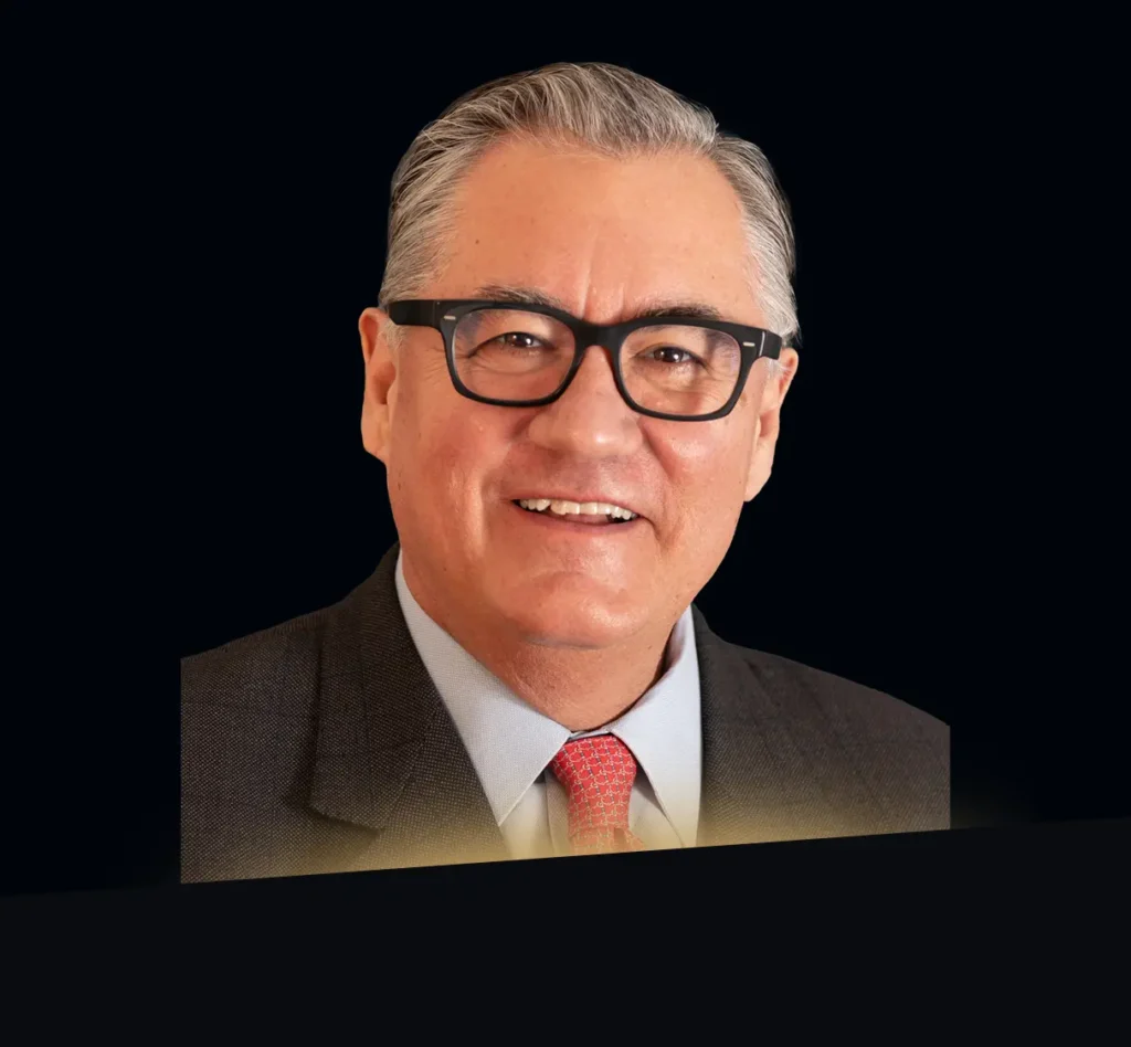Tomás Díaz de la Rubia headshot wearing dark grey blazer and red tie with gold glow at bottom of photo
