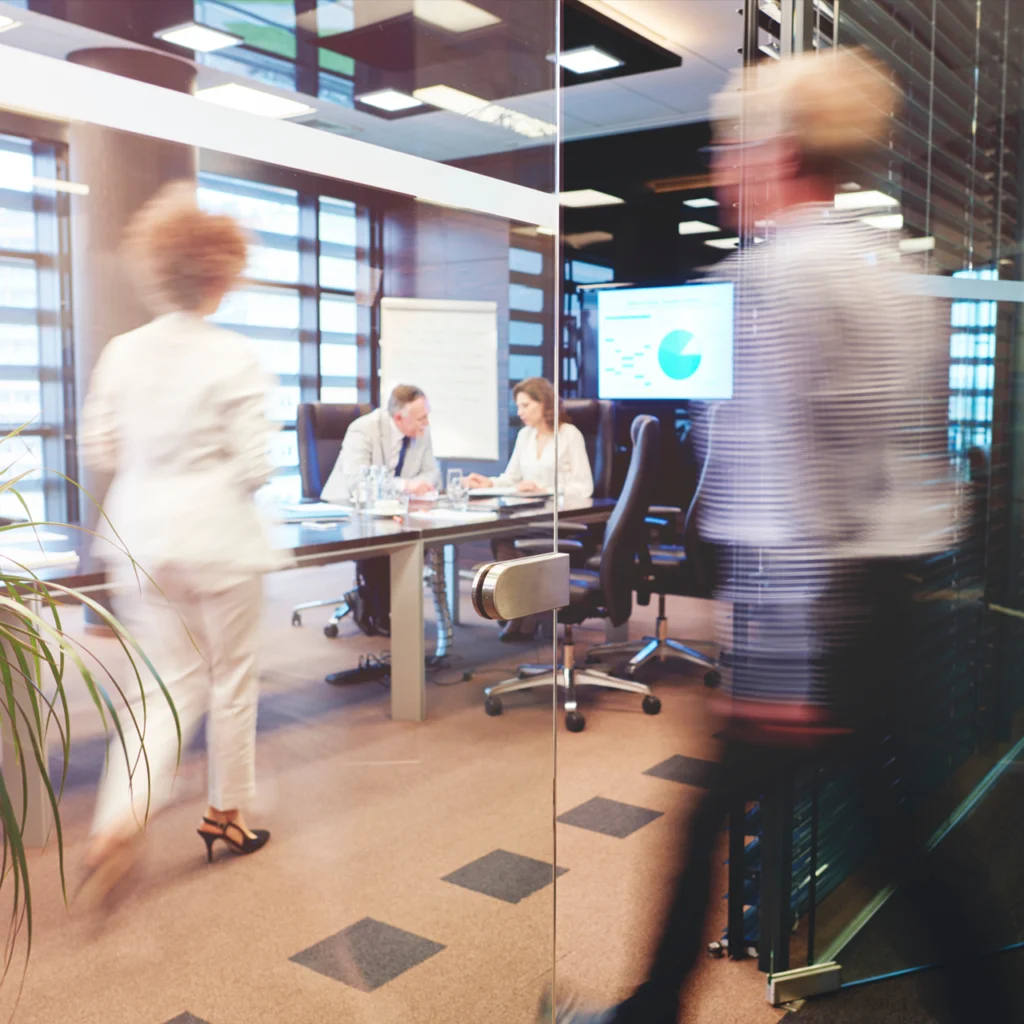 Glass doorway into office with corporate workers