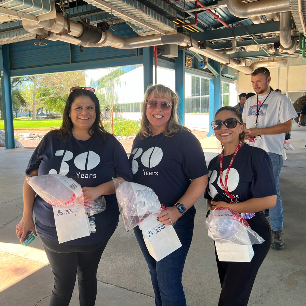 3 Tech Park employees posing for a photo at homecoming event