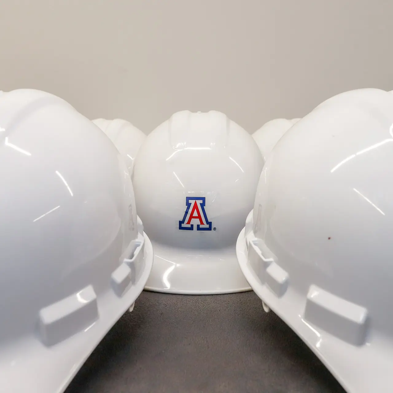 White construction hats with University of Arizona logo.