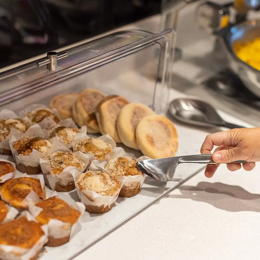 Breakfast pastries with a hand holding a utensil to grab one.
