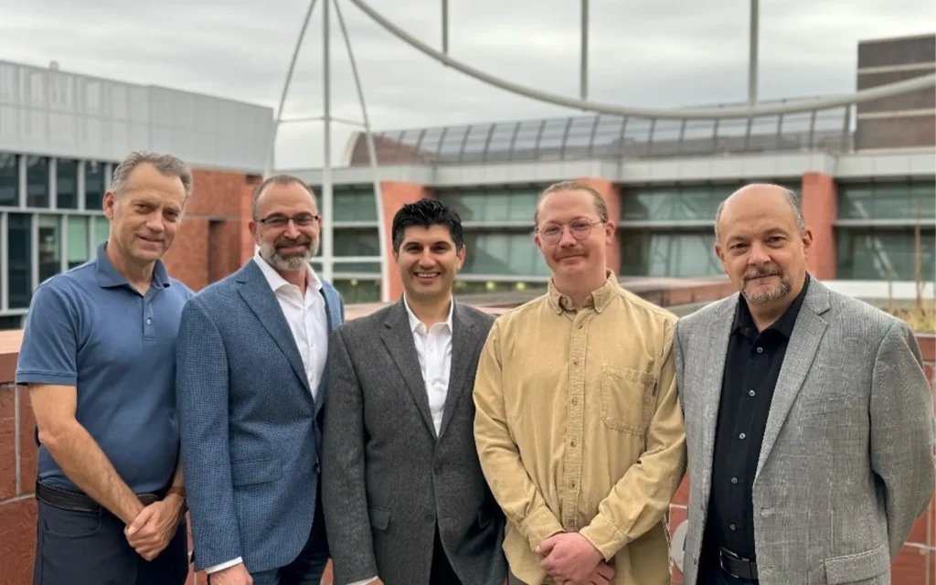 5 men dressed professionally posing for a photo.