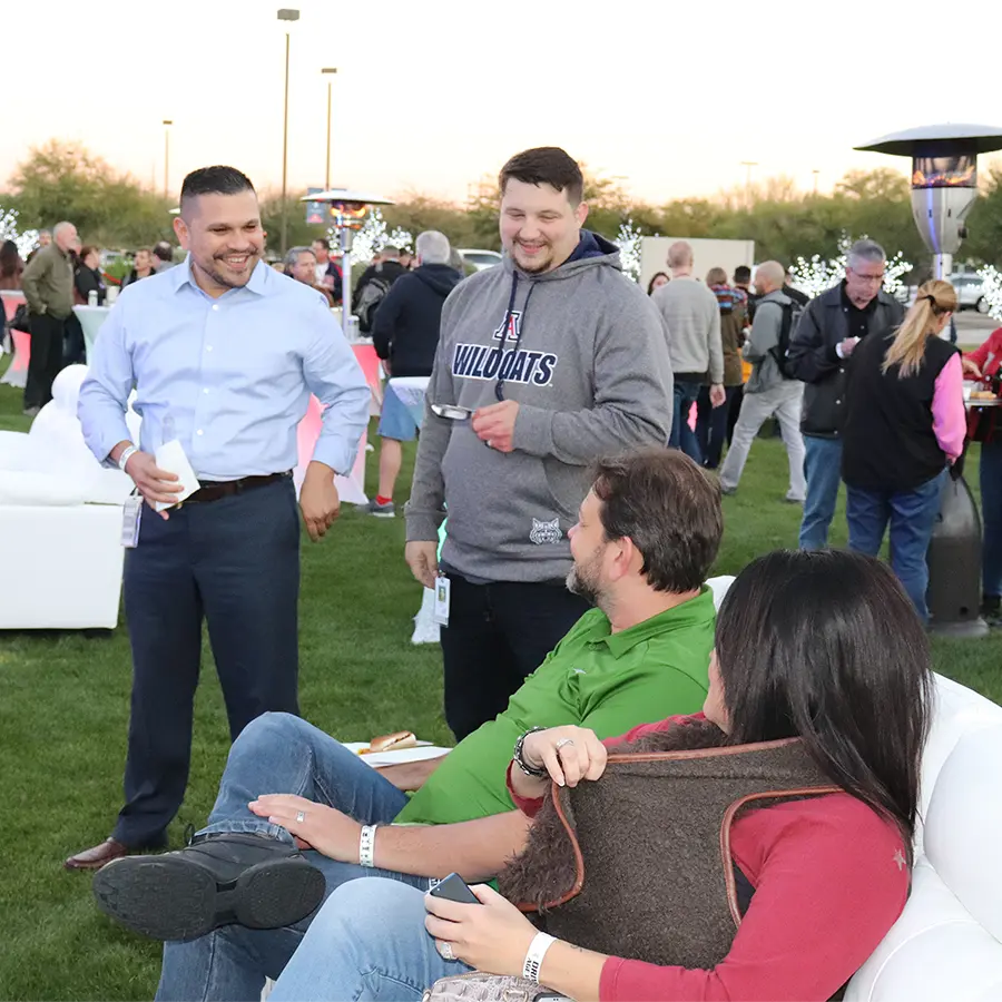 Four people talking at an outdoor event in the evening.