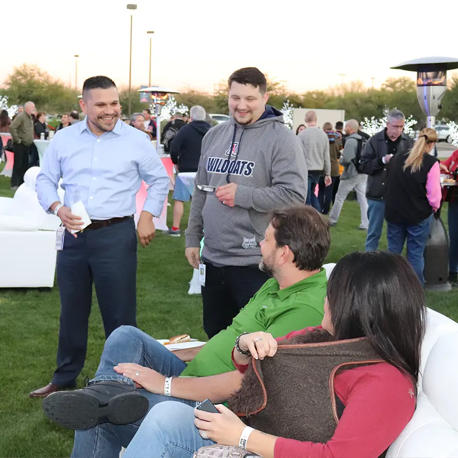 Four people talking at an outdoor event in the evening.