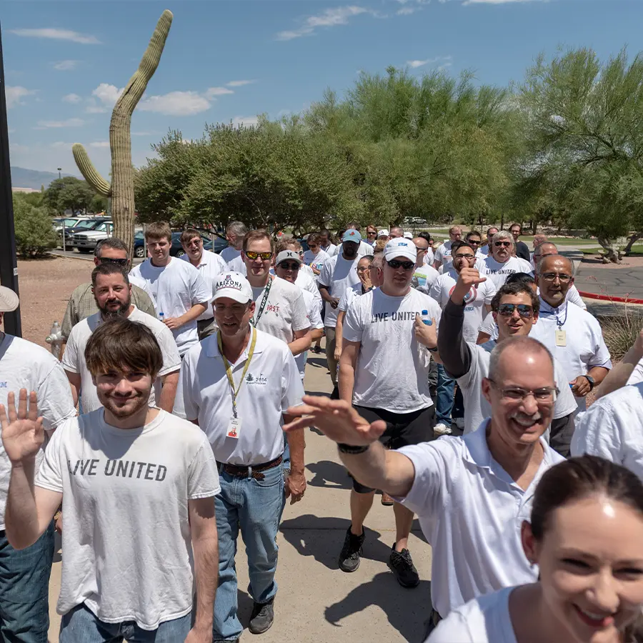 Group of people walking together wearing matching white t-shirts.
