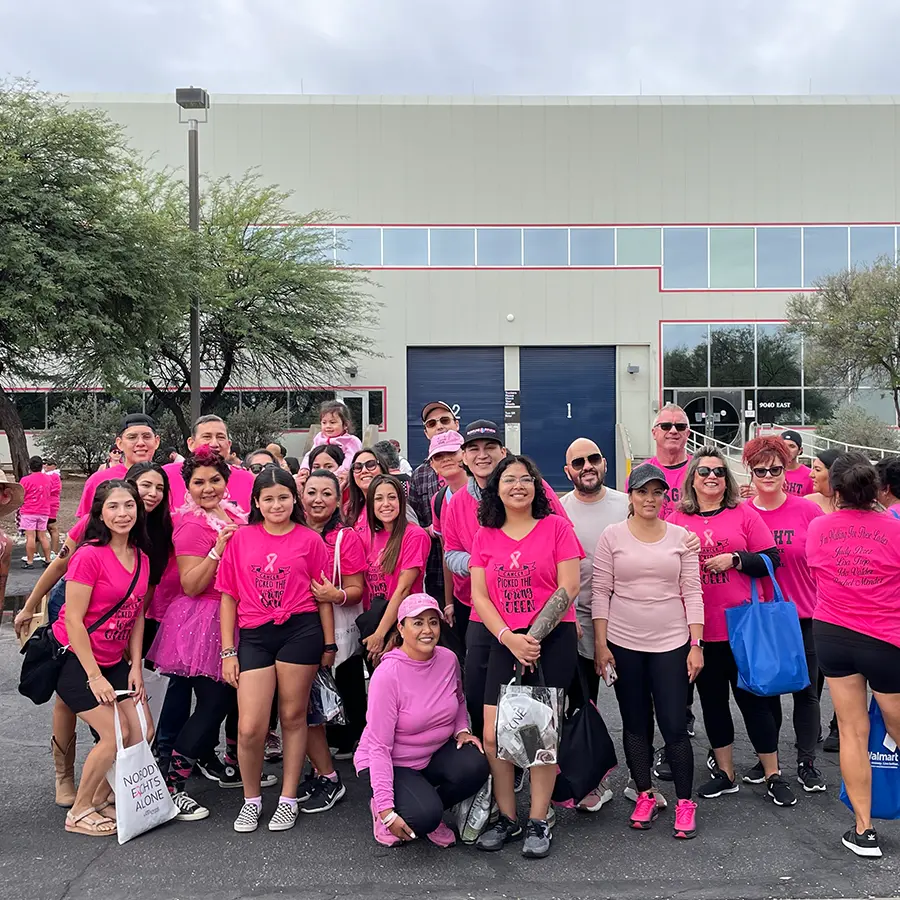 Group of people in pink shirts posing for a photo in front of a building.