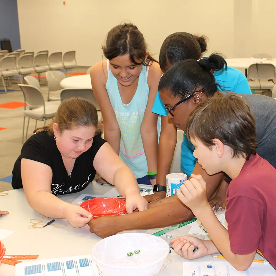 Children participating in a hands-on activity with an adult helping them.