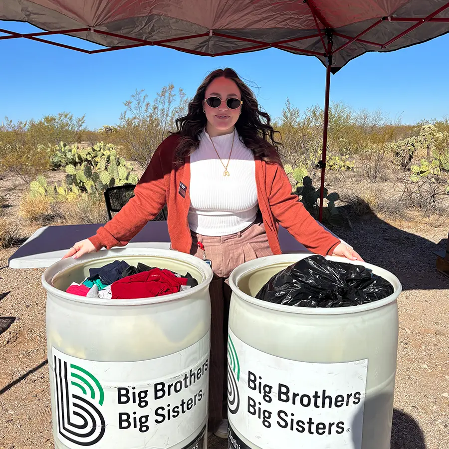 Woman standing behind two Big Brothers Big Sisters donation bins.