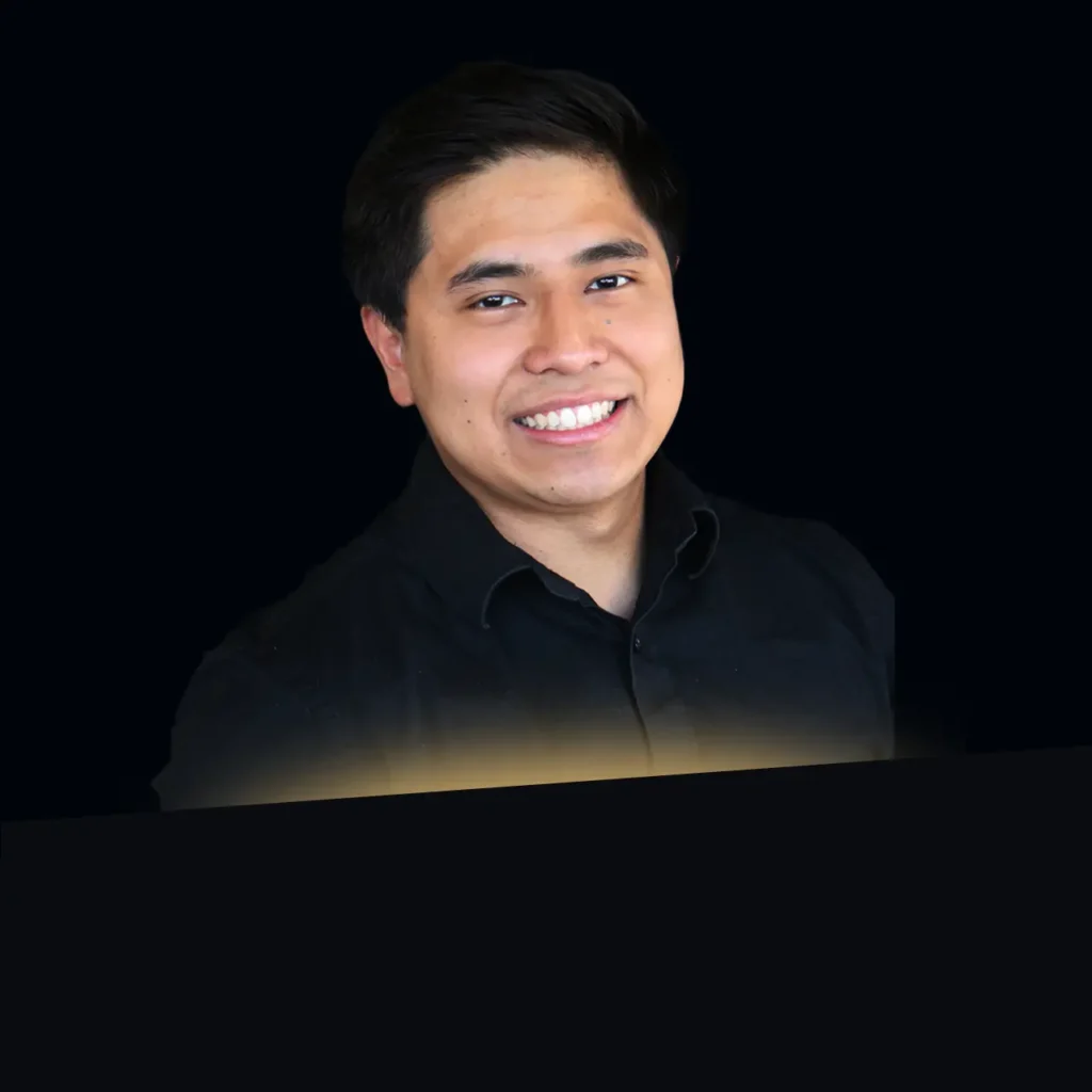 Smiling man with short dark hair wearing a black button-up shirt against a dark background.
