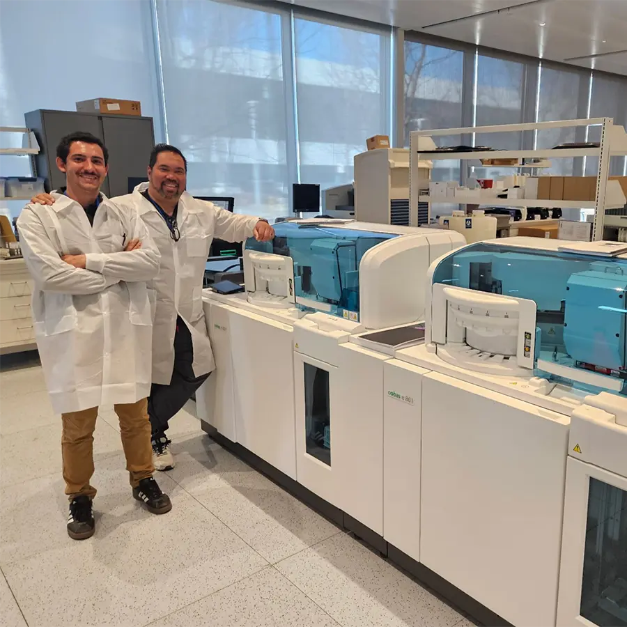 Two scientists standing next to a large medical machine.
